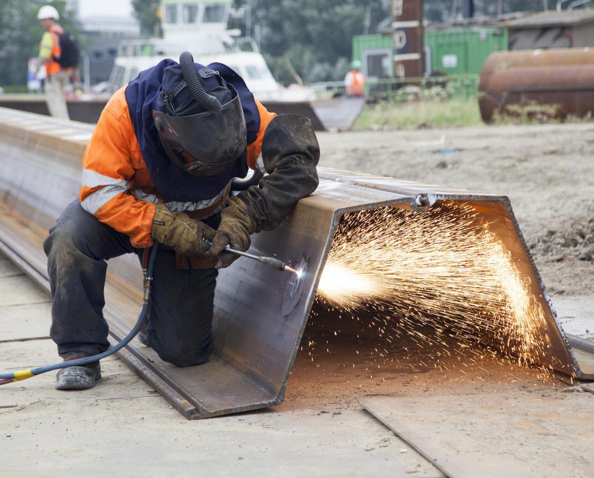 Werker bezig met lasapparaat op grote balk